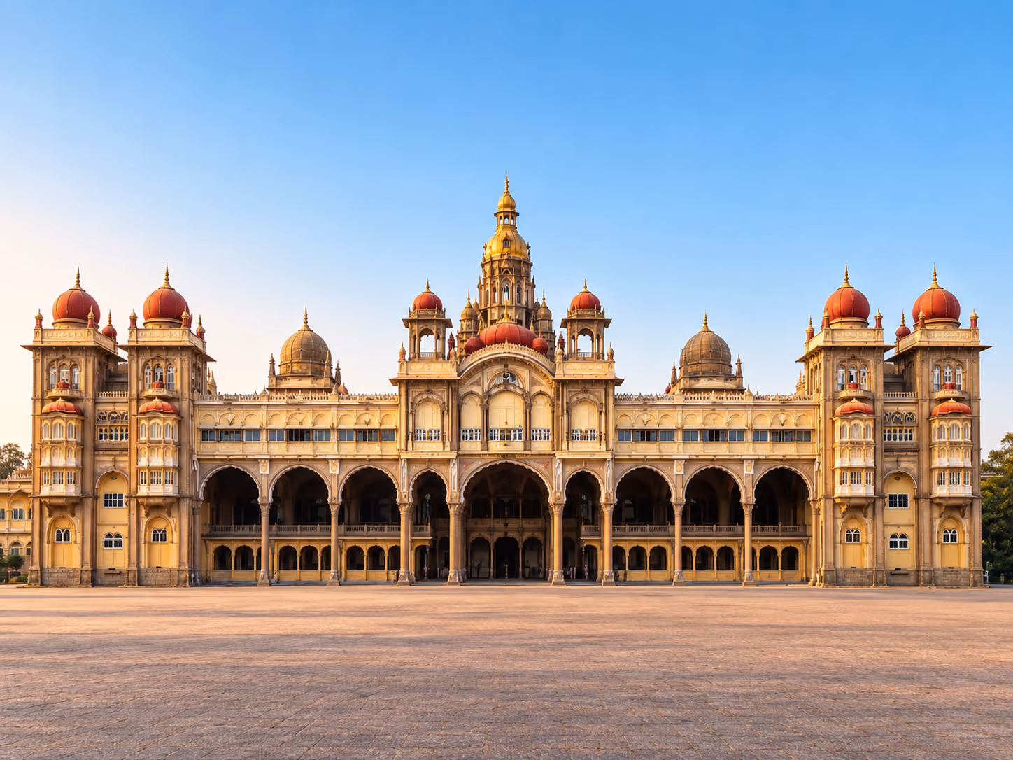 Mysore Palace ornate facade with golden domes and red cupolas in afternoon light